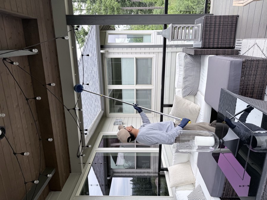Affordable Pest Pros technician removing spider webs from a covered patio ceiling
